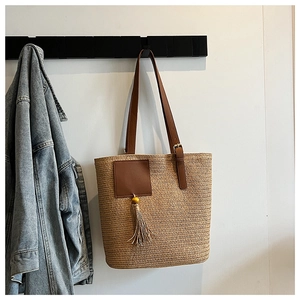 Detail of hand-woven straw tote with adjustable leather straps and decorative tassel
