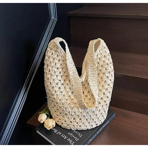 Close-up of a cream hollow-out woven crochet shoulder bag with a bohemian floral pattern