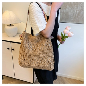 Detail of woven straw tote bag with intricate openwork pattern and colorful ethnic strap