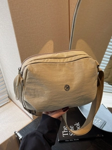 Sac bandoulière minimaliste en nylon beige avec bandoulière large et logo métallique chic