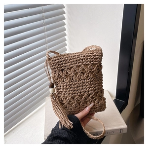 Detail of hand-woven straw bucket bag featuring intricate patterns and long tassels