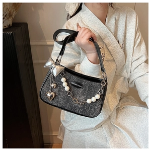 Détail du sac à main gris pailleté avec nœud argenté, breloque cœur et chaîne perle
