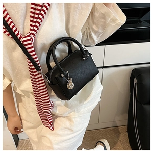 Détail du sac Boston noir en cuir grainé avec finitions argentées porté en bandoulière