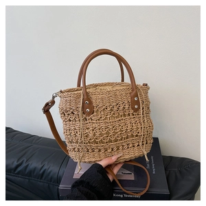 Detail view of woven straw tote with brown leather handles and drawstring lining