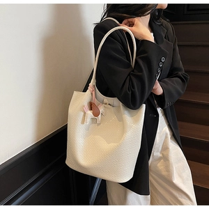 Close-up of off-white tote bag with textured weave pattern and cute horse charm