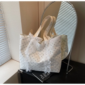 Détail d'un sac cabas blanc à pois avec bordures en dentelle et nœud en ruban décoratif
