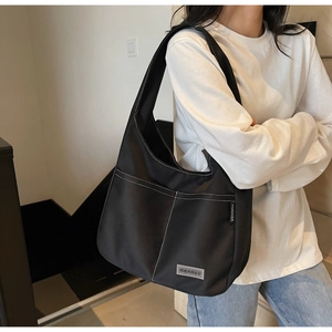 Detail of black tote bag with white contrast stitching and front double pockets