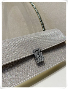 Detailed macro view of silver glitter clutch with metal handle and crystal buckle