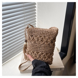 Detail of bohemian straw bucket bag with intricate openwork weave and wooden bead tassels
