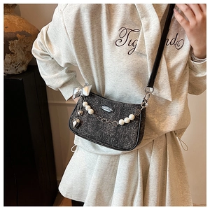 Détail du sac à bandoulière à paillettes noires avec chaîne perles et nœud argent