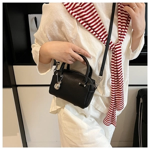 Détail d'un sac Boston en cuir grainé noir avec pendentif boule argentée et bandoulière