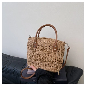 Close-up of woven straw bucket bag with brown leather handles and beige drawstring liner