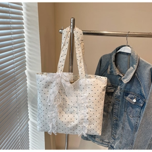 Détail du sac cabas blanc à pois avec des nœuds en dentelle superposés et des bordures