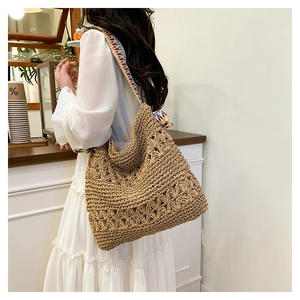 Detail of woven straw tote bag with geometric strap in a modern cafe setting