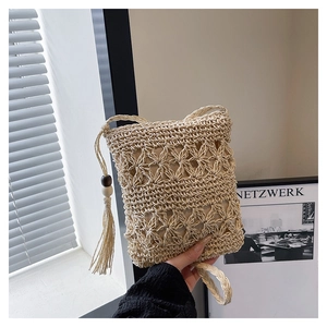 Close-up of bohemian woven straw bucket bag with tassels and wooden bead details