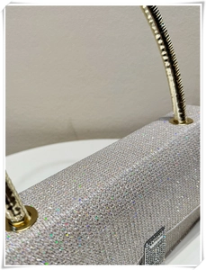 Close-up of glittery silver evening bag with gold circular handle and diamond clasp