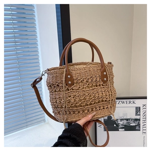 Close-up of woven straw handbag featuring brown leather handles and drawstring lining