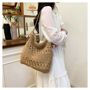 Close-up of bohemian woven straw tote with hollow floral patterns and colorful straps