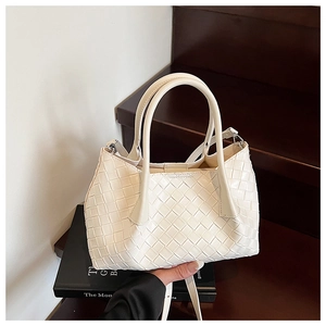 Détail d'un sac cabas tissé blanc à motif damier avec doubles anses sur un escalier