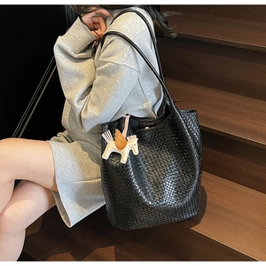 Detail of black woven tote bag with a colorful horse pendant on a leather shoulder bag