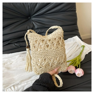 Detail of woven bucket bag with fringe tassels and wooden bead on beige crochet texture