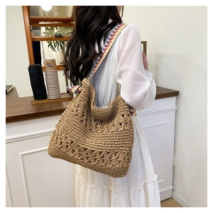 Close-up of straw woven tote bag with a colorful geometric ethnic style shoulder strap