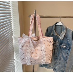 Détail du cabas en toile à pois roses avec froufrous en dentelle et grand nœud décoratif