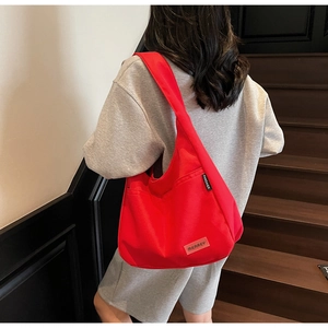 Dynamic view of a large red canvas tote bag worn by a model on wooden stairs