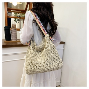 Detail of hollow floral woven straw bag with colorful geometric patterned wide strap