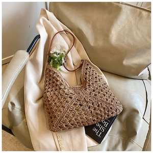 Close-up of woven straw tote bag featuring detailed hollow diamond patterns and leather straps