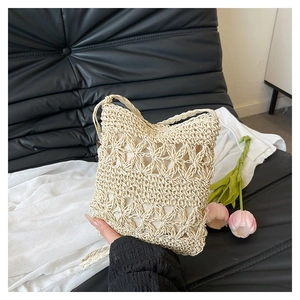 Close-up of beige woven bucket bag featuring hollow floral knit patterns and fabric lining
