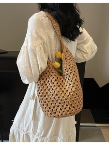 Hollow out woven straw shoulder bag in hobo style with fresh yellow tulips inside