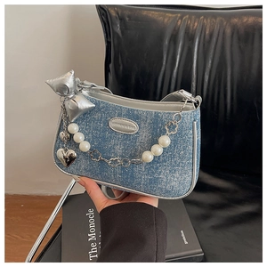 Détail du sac à main bleu à motif flocon avec nœud argenté, breloques cœur et perles
