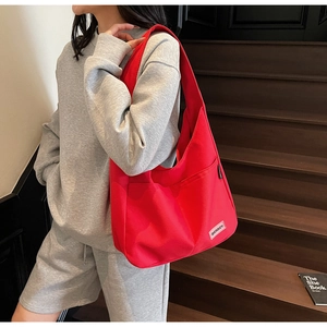 Detail of red canvas hobo bag featuring dual front pockets and stitched brand label