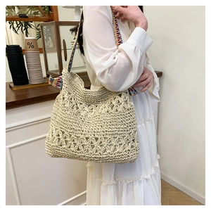 Detail of hand-woven straw tote bag with colorful decorative strap on a shoulder