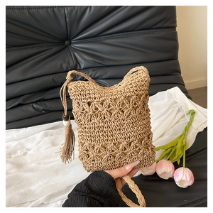 Detailed close-up of bohemian woven bucket bag with tassels and wooden bead accents