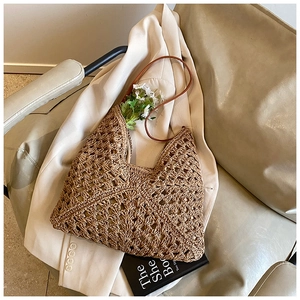 Detail of bohemian straw tote bag with crochet hollow patterns and brown leather straps