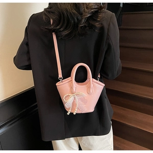 Detail of pink mini bucket bag with lace bow, pearl chain and lychee leather texture