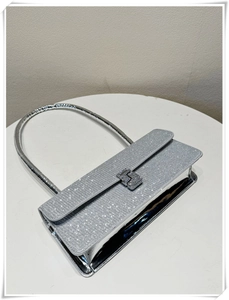 Detail shot of the rectangular silver sequin handbag with a metallic clasp and handle