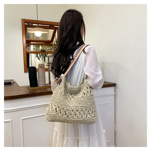 Close-up of beige crochet straw tote bag with colorful ethnic style shoulder strap