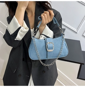 Detail of light blue denim shoulder bag with silver chain and square buckle closure