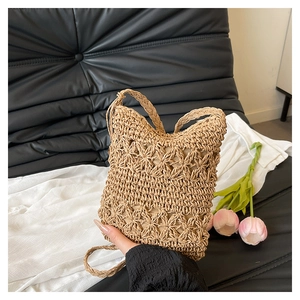Macro view of hand-woven hollow flower pattern on summer straw bucket crossbody bag