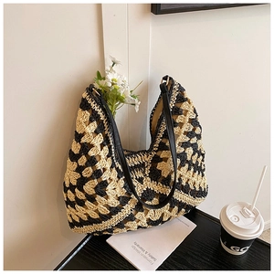 Detail of hand-woven straw tote bag featuring contrast diamond pattern and leather straps