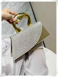 Detailed macro view of silver rhinestone handbag with artistic gold metal handle