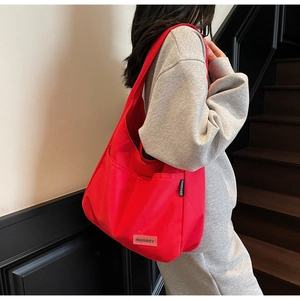 Detail of red canvas tote bag showing the textured fabric and brand logo patches