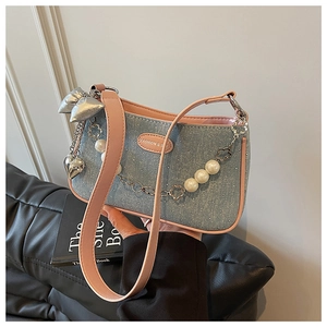 Détail du sac en jean avec garniture en cuir rose, chaîne de perles et nœud argenté