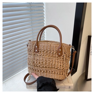 Detail of crochet straw tote bag with brown leather handles on a sunlit window sill