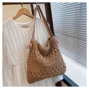 Detail of bohemian straw tote bag with floral openwork and colorful geometric strap