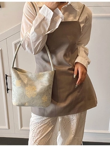 Chic light green floral jacquard bucket bag styled with an elegant outfit on a model
