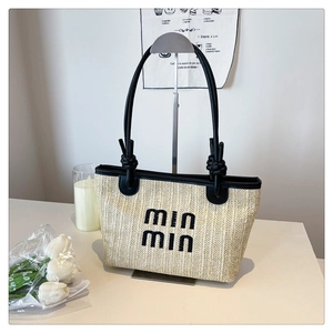 Detail of woven straw tote bag with black leather handles and MIN MIN embroidery logo